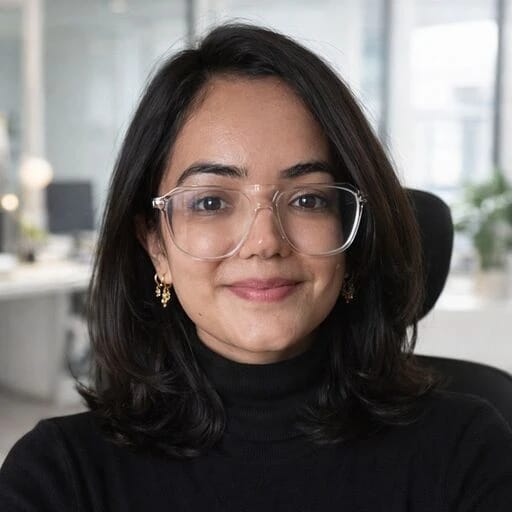 Smiling woman wearing glasses and a black turtleneck in an office.