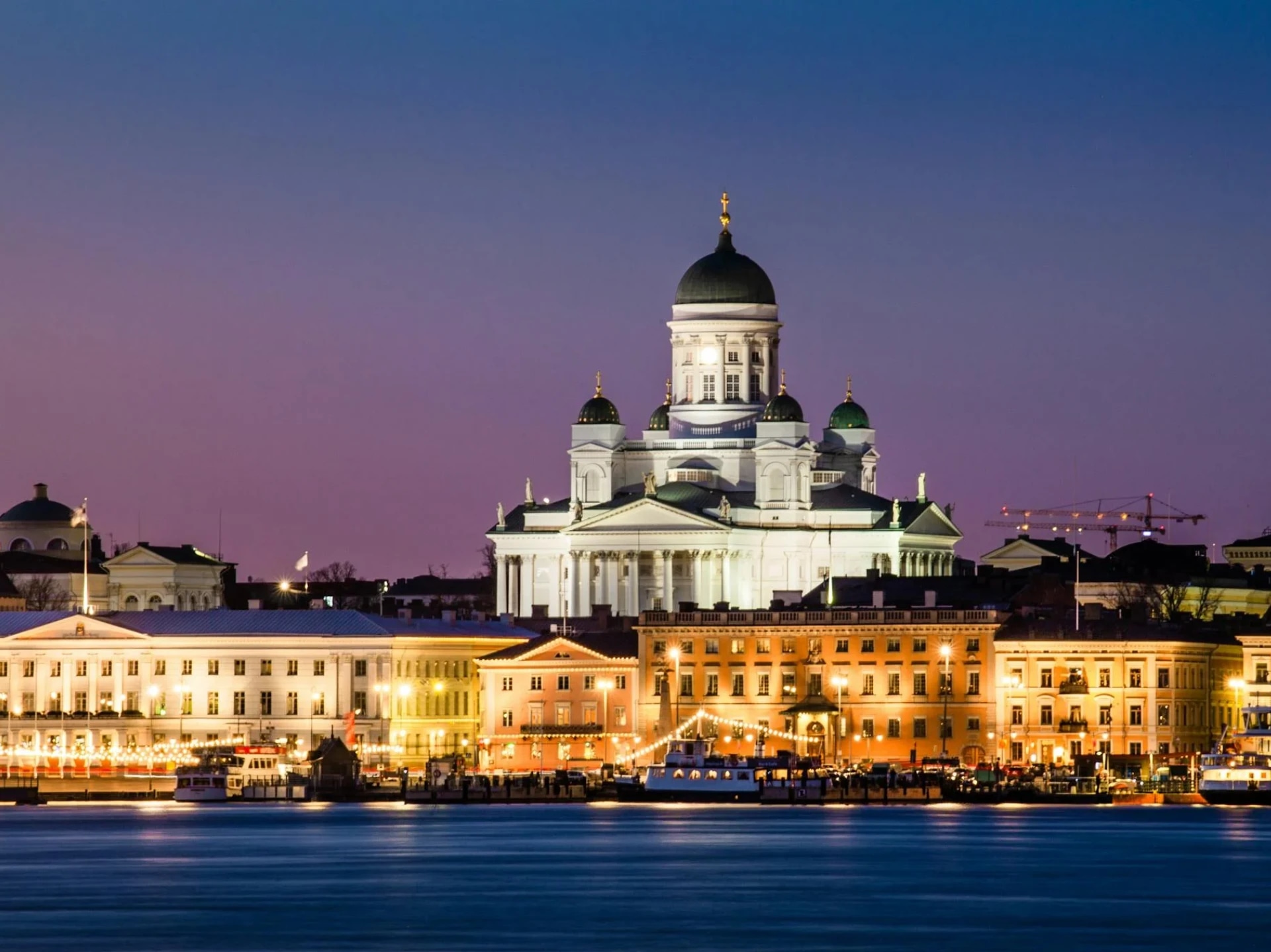Helsinki Cathedral illuminated at dusk, viewed from the waterfront.