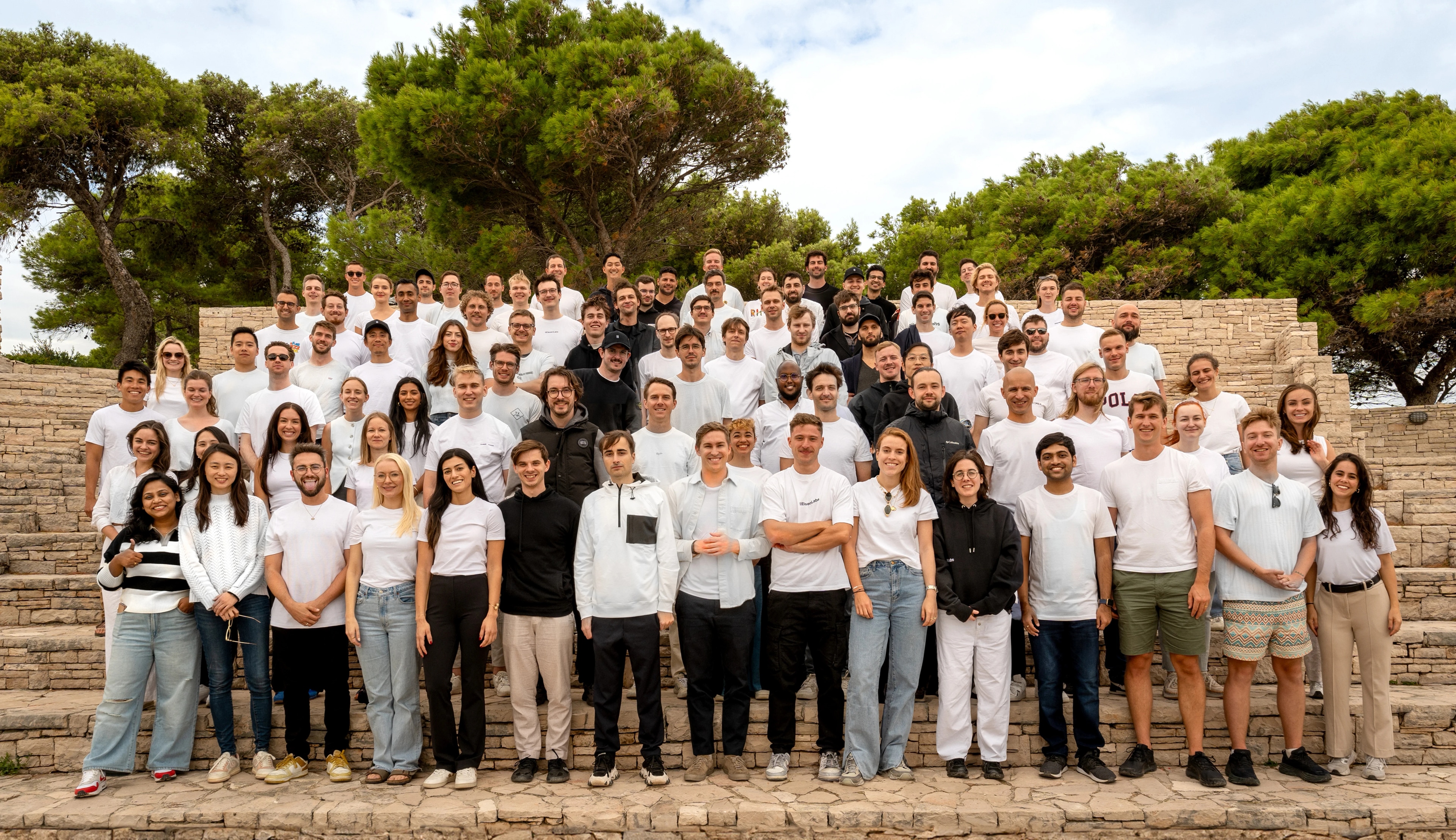 Group of people standing on stone steps outdoors, smiling at the camera.