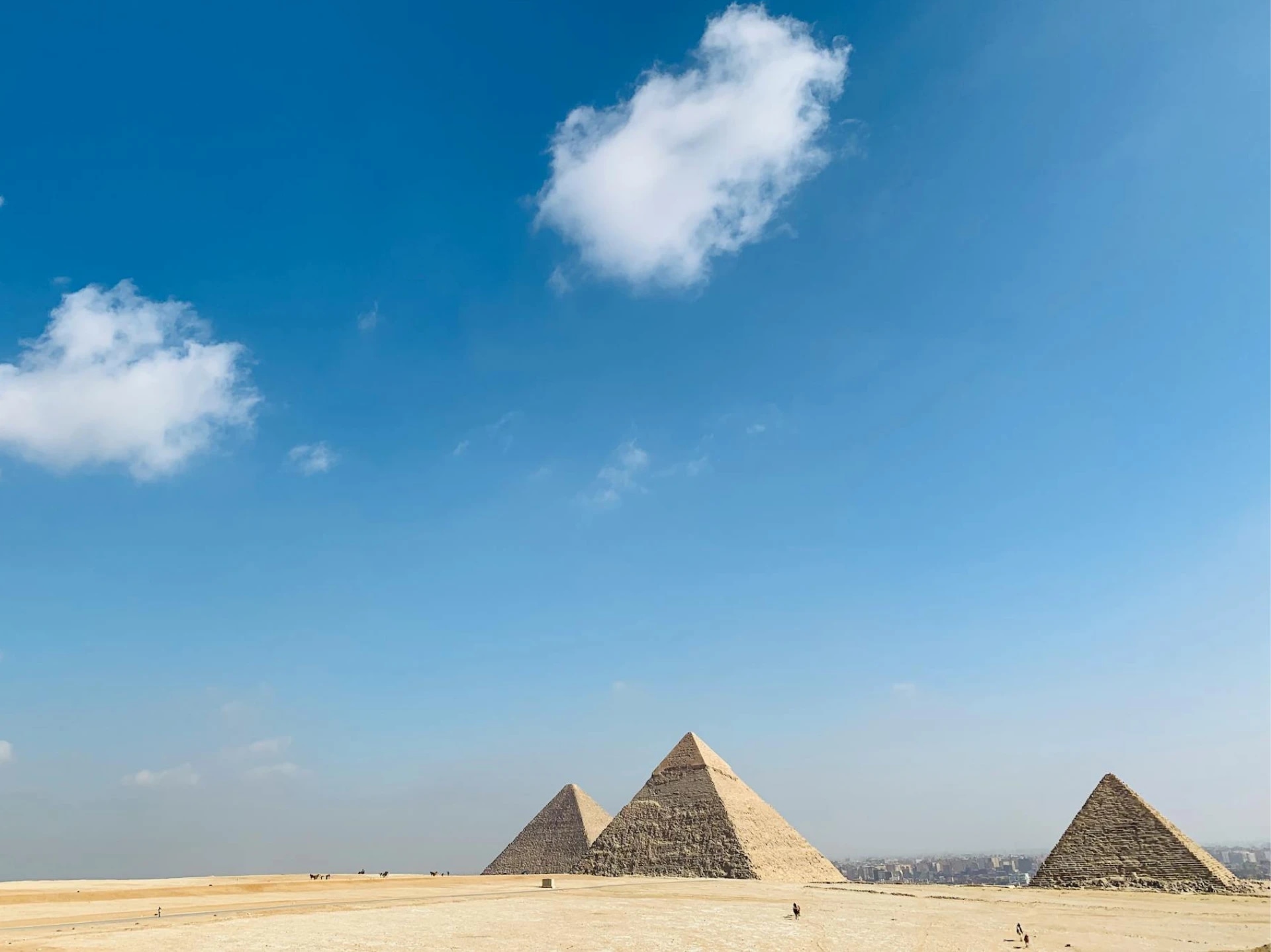 Pyramids of Giza under a blue sky with scattered clouds.